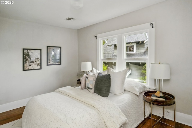 bedroom featuring visible vents, baseboards, and wood finished floors