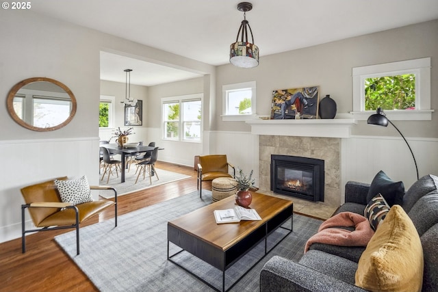 living area featuring a tiled fireplace, wood finished floors, and wainscoting