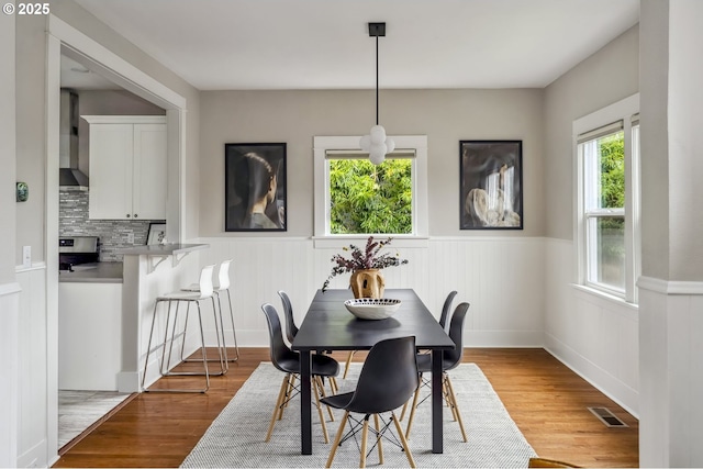 dining room with a wainscoted wall, wood finished floors, and visible vents