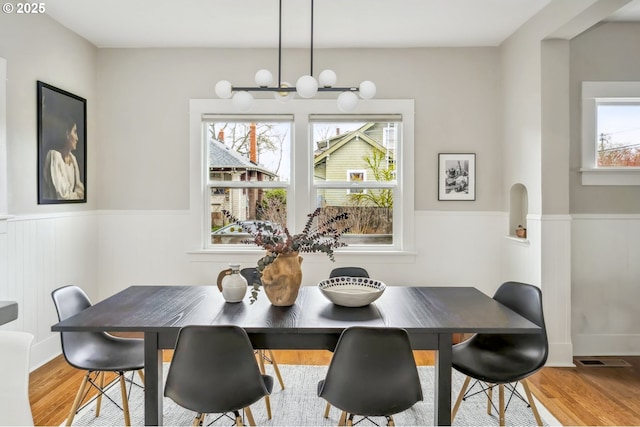 dining area with a wealth of natural light, wainscoting, and wood finished floors