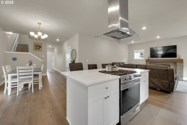 3783 Rockcress Rd, Eugene, OR 97403 - kitchen with stainless steel gas stove, island range hood, open floor plan, light wood-style flooring, and a center island