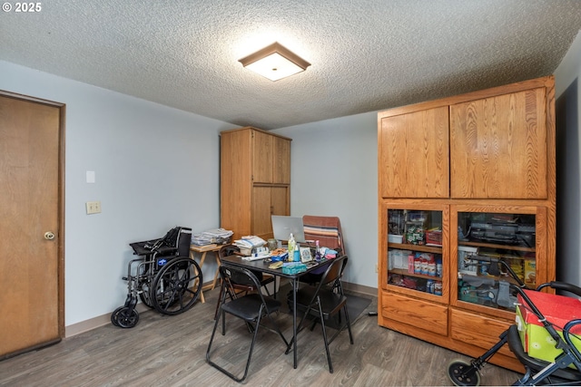 dining space featuring light wood-style floors, an office area, a textured ceiling, and baseboards