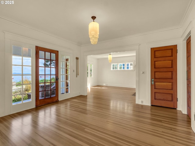 entryway with a chandelier, wood finished floors, ornamental molding, and baseboards