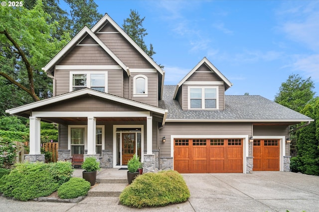 4975 SW Laurelwood Ave, Portland, OR 97225 - craftsman inspired home with covered porch, stone siding, concrete driveway, a shingled roof, and an attached garage