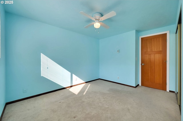 carpeted empty room with ceiling fan and baseboards