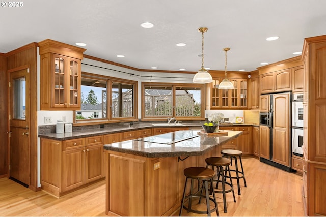 kitchen featuring light wood-style floors, black electric cooktop, a kitchen breakfast bar, and a center island