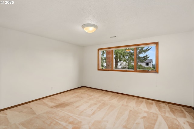 unfurnished room featuring baseboards, a textured ceiling, visible vents, and light colored carpet