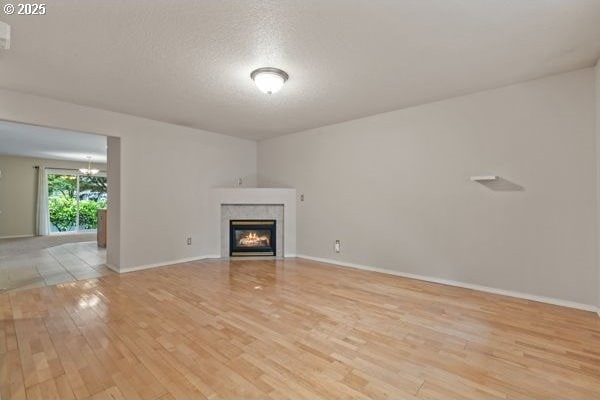 17504 SE 16th Cir, Vancouver, WA 98683 - unfurnished living room featuring light wood-type flooring, a chandelier, a glass covered fireplace, and baseboards