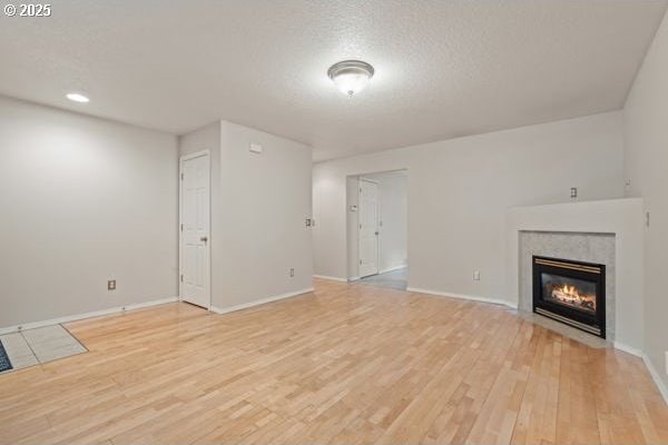 17504 SE 16th Cir, Vancouver, WA 98683 - unfurnished living room with light wood finished floors, a fireplace with flush hearth, a textured ceiling, and baseboards