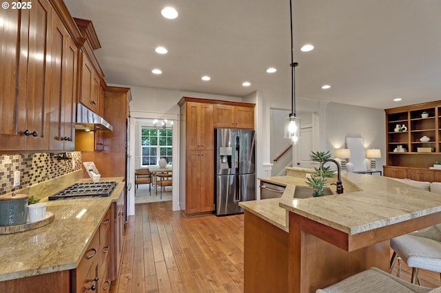 1734 NW Saltzman Rd, Portland, OR 97229 - kitchen featuring stainless steel appliances, a sink, brown cabinetry, light wood-type flooring, and under cabinet range hood