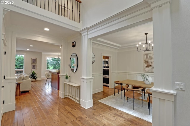 1734 NW Saltzman Rd, Portland, OR 97229 - foyer entrance with light wood-style floors, ornate columns, a chandelier, a wainscoted wall, and recessed lighting