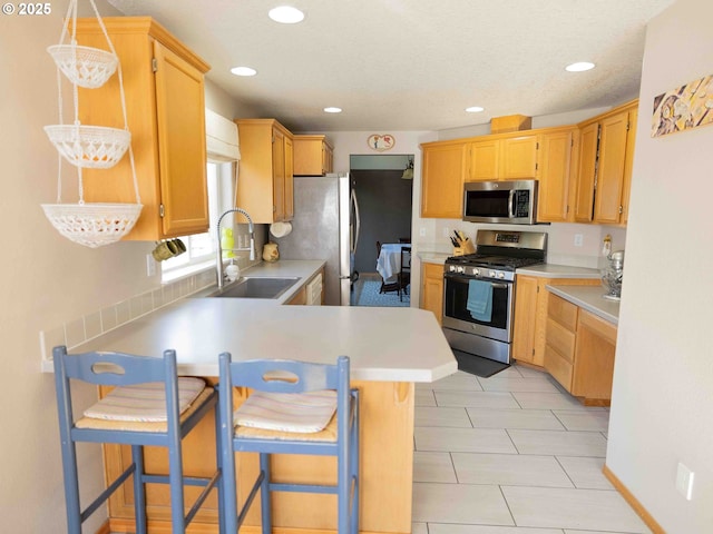 3135 SE 26th St, Gresham, OR 97080 - kitchen featuring appliances with stainless steel finishes, a peninsula, light countertops, recessed lighting, and a breakfast bar