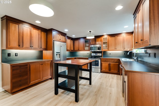 kitchen with recessed lighting, brown cabinetry, a sink, light wood-style floors, and appliances with stainless steel finishes