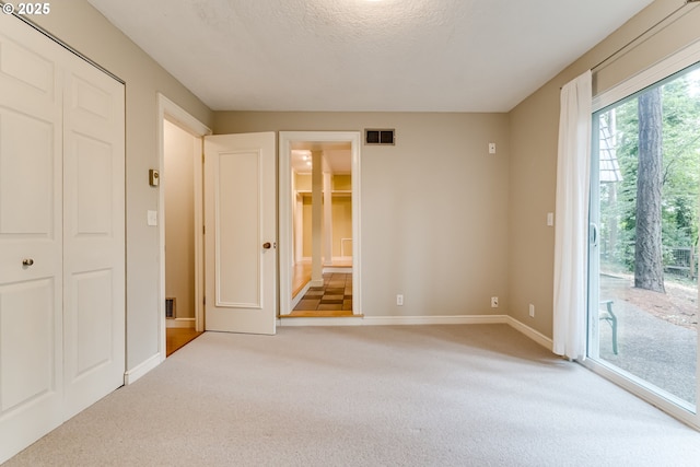 unfurnished bedroom featuring access to exterior, ensuite bathroom, visible vents, baseboards, and light carpet