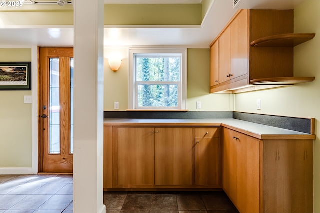 kitchen with dark tile patterned flooring, open shelves, and baseboards