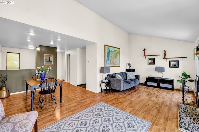 living room featuring baseboards, wood finished floors, and vaulted ceiling