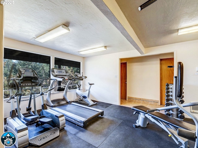 exercise room with baseboards and a textured ceiling