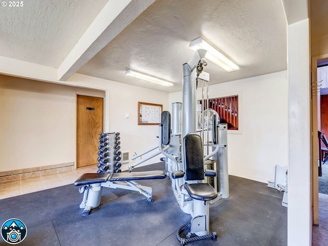 exercise area with baseboards and a textured ceiling