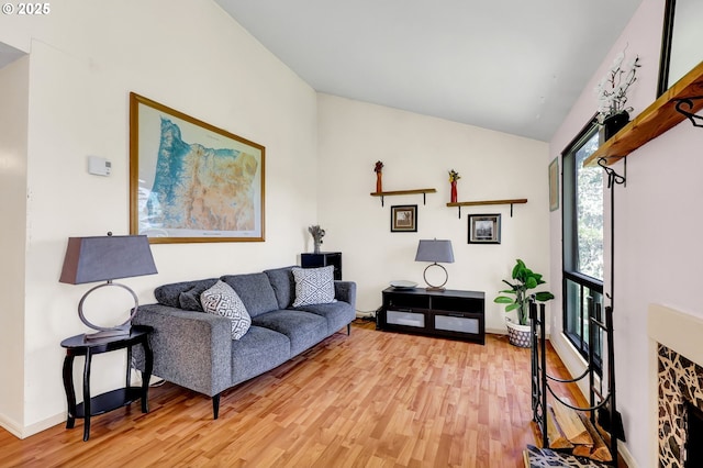 living room with baseboards, light wood-style flooring, and vaulted ceiling