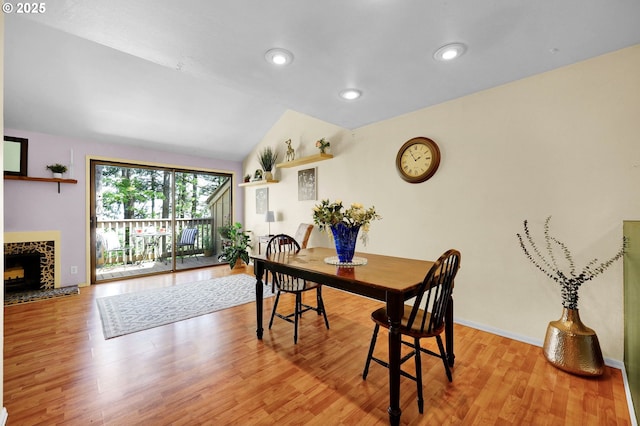 dining area with a tiled fireplace, recessed lighting, baseboards, wood finished floors, and vaulted ceiling