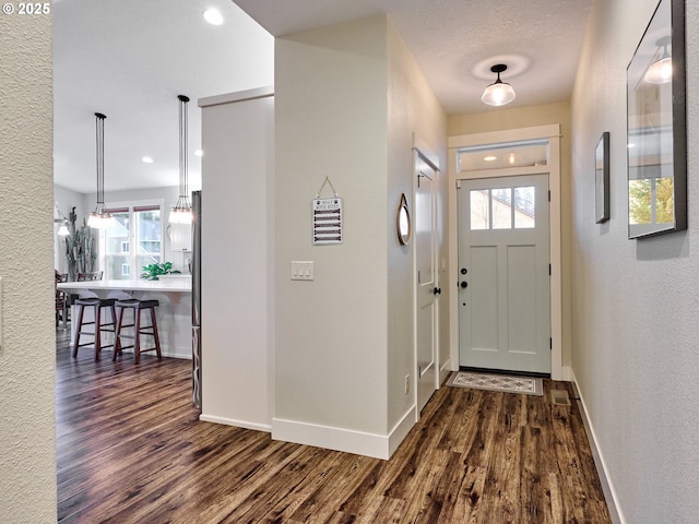 entrance foyer featuring dark wood-style floors, a textured wall, and baseboards