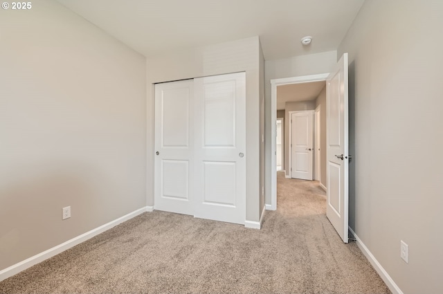 unfurnished bedroom with a closet and light colored carpet