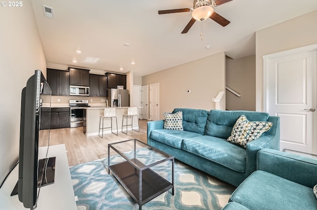 living room with sink, ceiling fan, and light hardwood / wood-style flooring