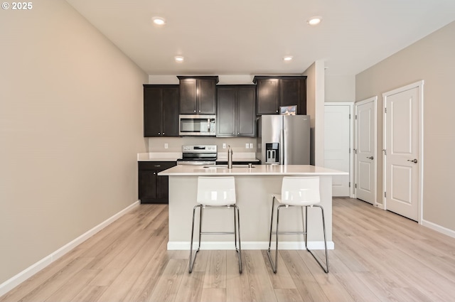 kitchen with a center island with sink, light hardwood / wood-style flooring, sink, a kitchen breakfast bar, and stainless steel appliances