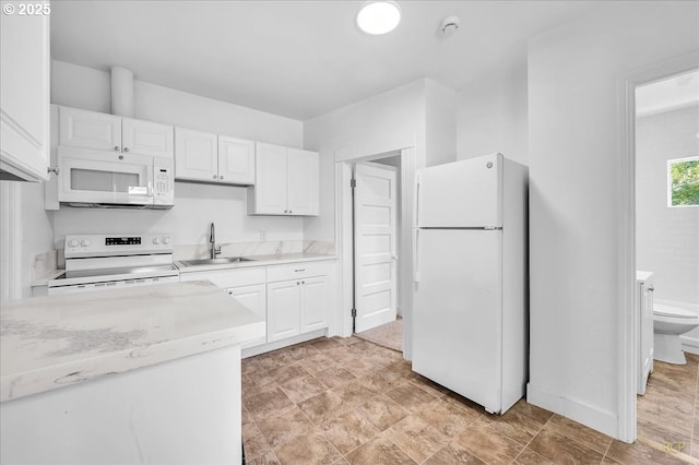 kitchen with white appliances, a sink, white cabinetry, and baseboards