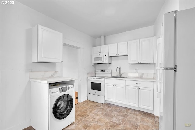 kitchen with white appliances, washer / dryer, a sink, light countertops, and white cabinetry
