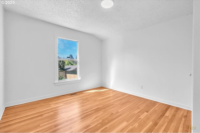 empty room featuring a textured ceiling, wood finished floors, and baseboards