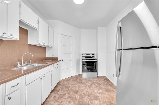 kitchen featuring appliances with stainless steel finishes, a sink, and white cabinets