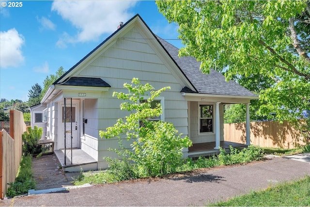 view of front of house featuring roof with shingles and fence