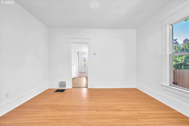 unfurnished room featuring a textured ceiling, wood finished floors, and baseboards