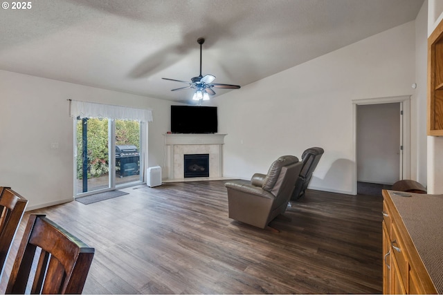 living area with dark wood finished floors, vaulted ceiling, a fireplace, and ceiling fan