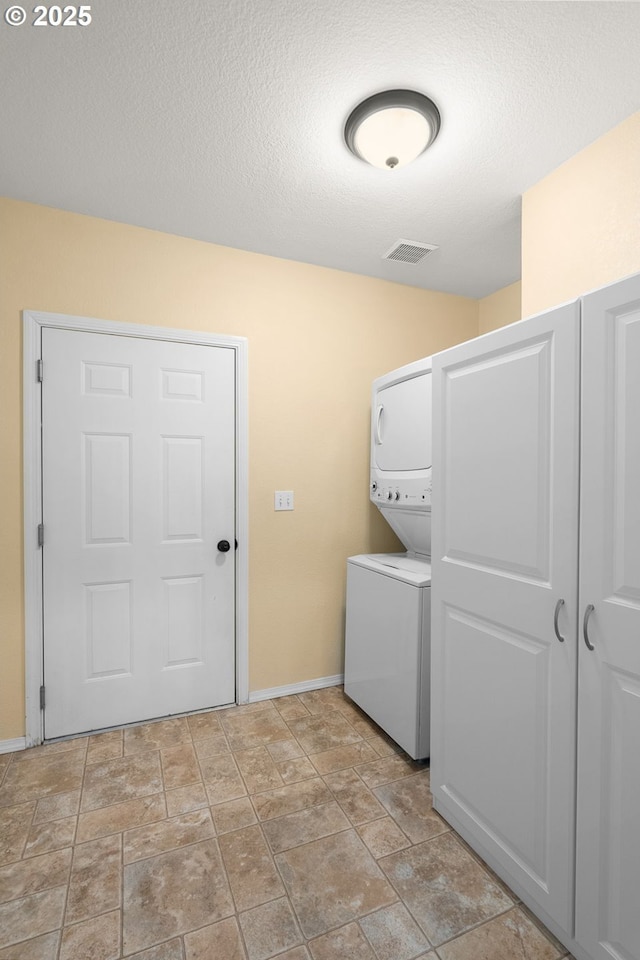 1231 NE Horizon Loop Unit 203, Hillsboro, OR 97124 - washroom with estacked washer and dryer, baseboards, light stone finish floors, and a textured ceiling