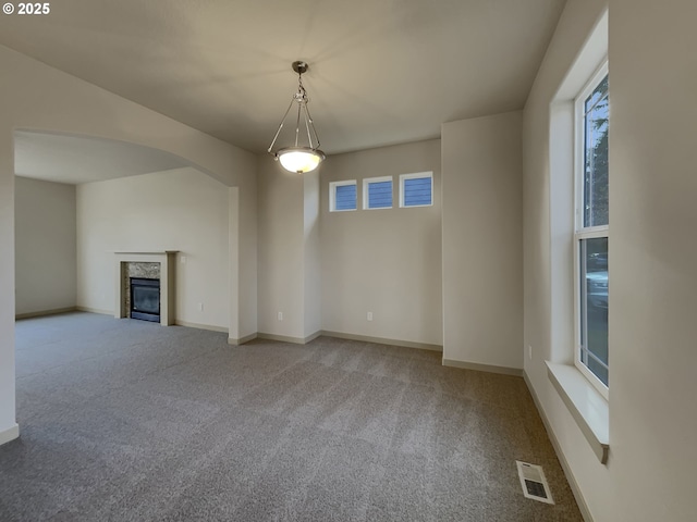 unfurnished living room with carpet floors, a wealth of natural light, and a premium fireplace