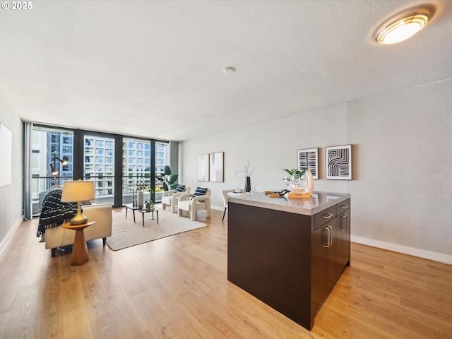 255 SW Harrison St Unit 9C, Portland, OR 97201 - kitchen featuring light wood-type flooring, a center island, baseboards, and open floor plan