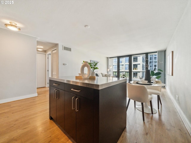 255 SW Harrison St Unit 9C, Portland, OR 97201 - kitchen featuring stainless steel counters, light wood-style floors, baseboards, and a center island