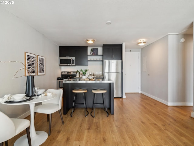 255 SW Harrison St Unit 9C, Portland, OR 97201 - kitchen featuring appliances with stainless steel finishes, dark cabinets, open shelves, and light wood-style flooring