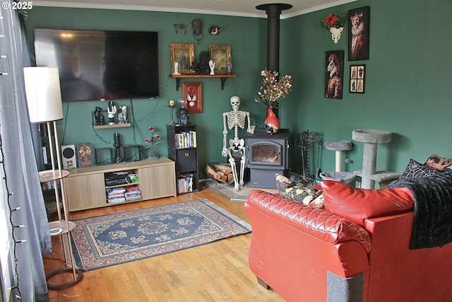 living room with hardwood / wood-style flooring, crown molding, and a wood stove