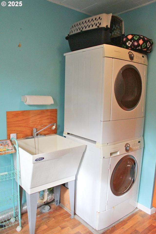 laundry room with stacked washer / drying machine and light wood-type flooring