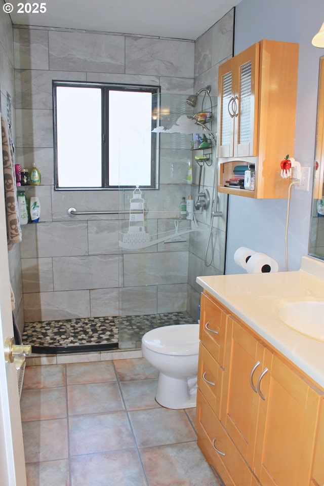 bathroom featuring tile patterned floors, vanity, toilet, and a tile shower