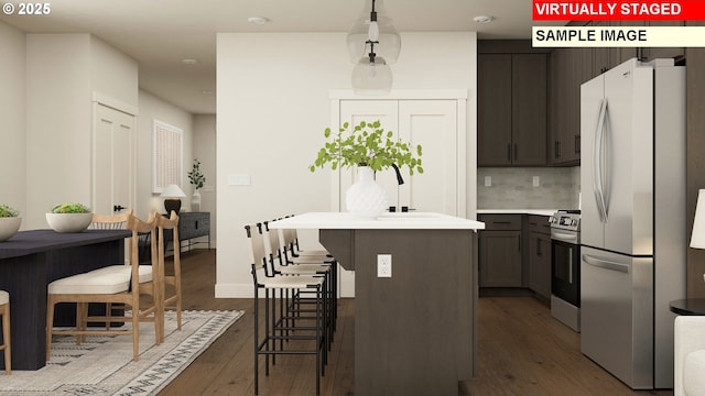 kitchen with freestanding refrigerator, a breakfast bar area, range, a kitchen island, and dark wood-style floors