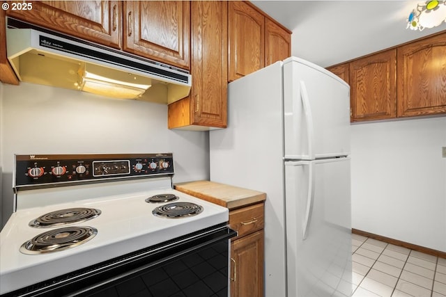 kitchen with light tile patterned floors, range with electric cooktop, and white fridge