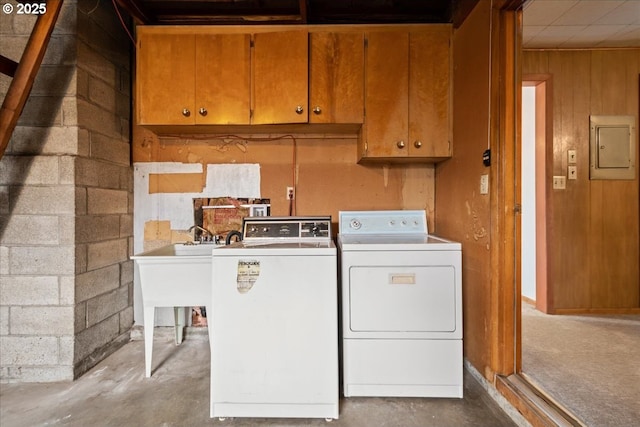 laundry room with cabinets, washing machine and dryer, electric panel, and wood walls