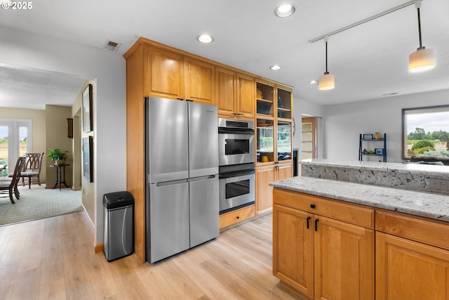 8747 S Heinz Rd, Canby, OR 97013 - kitchen with stainless steel appliances, light wood finished floors, light stone counters, brown cabinets, and recessed lighting