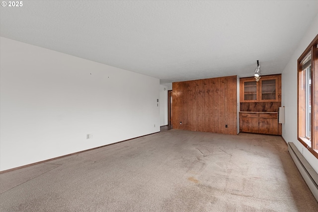 carpeted empty room featuring a baseboard heating unit