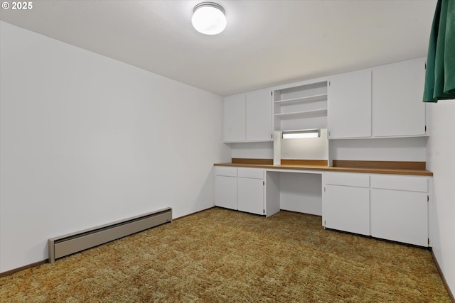 kitchen with white cabinetry, a baseboard heating unit, and built in desk