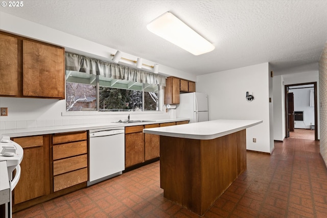 kitchen featuring a center island, sink, a textured ceiling, and white appliances